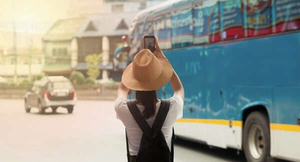 Autobús turístico - Mujer haciendo turismo tomándole foto al trasporte turístico reconocido como uno de los mejores autobús turístico de Valencia