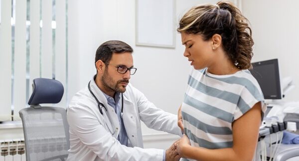Proctólogos - Médico proctólogo reconocido como uno de los mejores proctólogos de Valencia evaluando a una mujer en consulta de proctología por problemas en el colon