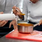 Escuelas de gastronomía - Cheff de academia de gastronomía enseñando a un cocinero en una de las mejores escuelas de gastronomía de Valencia