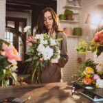 Floristerías - Mujer experta en arreglos florales armando un ramo de flores en una de las mejores floristerías de Valencia
