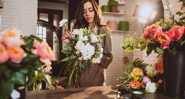 Floristerías - Mujer experta en arreglos florales armando un ramo de flores en una de las mejores floristerías de Valencia