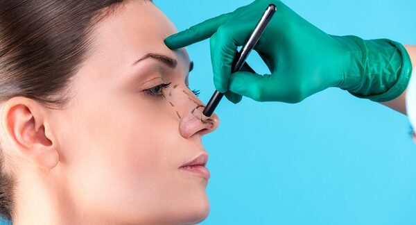 en una de las clínicas de rinoplastia, un doctor marca líneas en la nariz de una paciente que se hará este procedimiento
