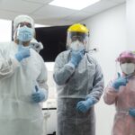 especialistas en enfermedades infecciosas vestidos con trajes especiales posan para una foto