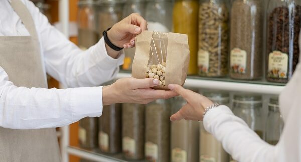 una de las tiendas a granel, un vendedor le dan en una bolsa con frutos secos a un cliente