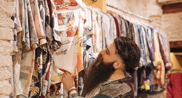 en una de las tiendas de ropa vintage, un hombre revisa opciones en camisas