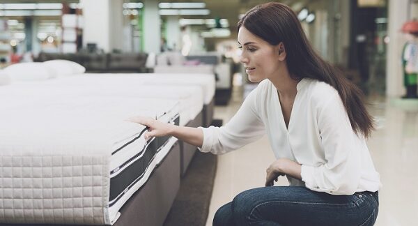 de las tiendas de colchones, una mujer revisa un colchón en una tienda