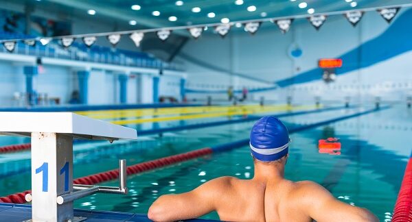 mejores escuelas de natación - hombre recostado en la orilla de una piscina olímpica